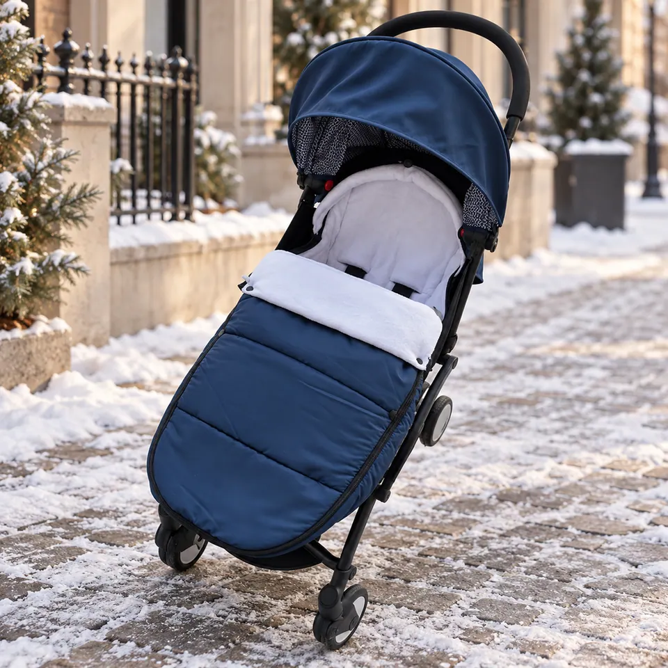 Chancelière KodoCozy bleu nuit sur une poussette, dans une rue enneigée